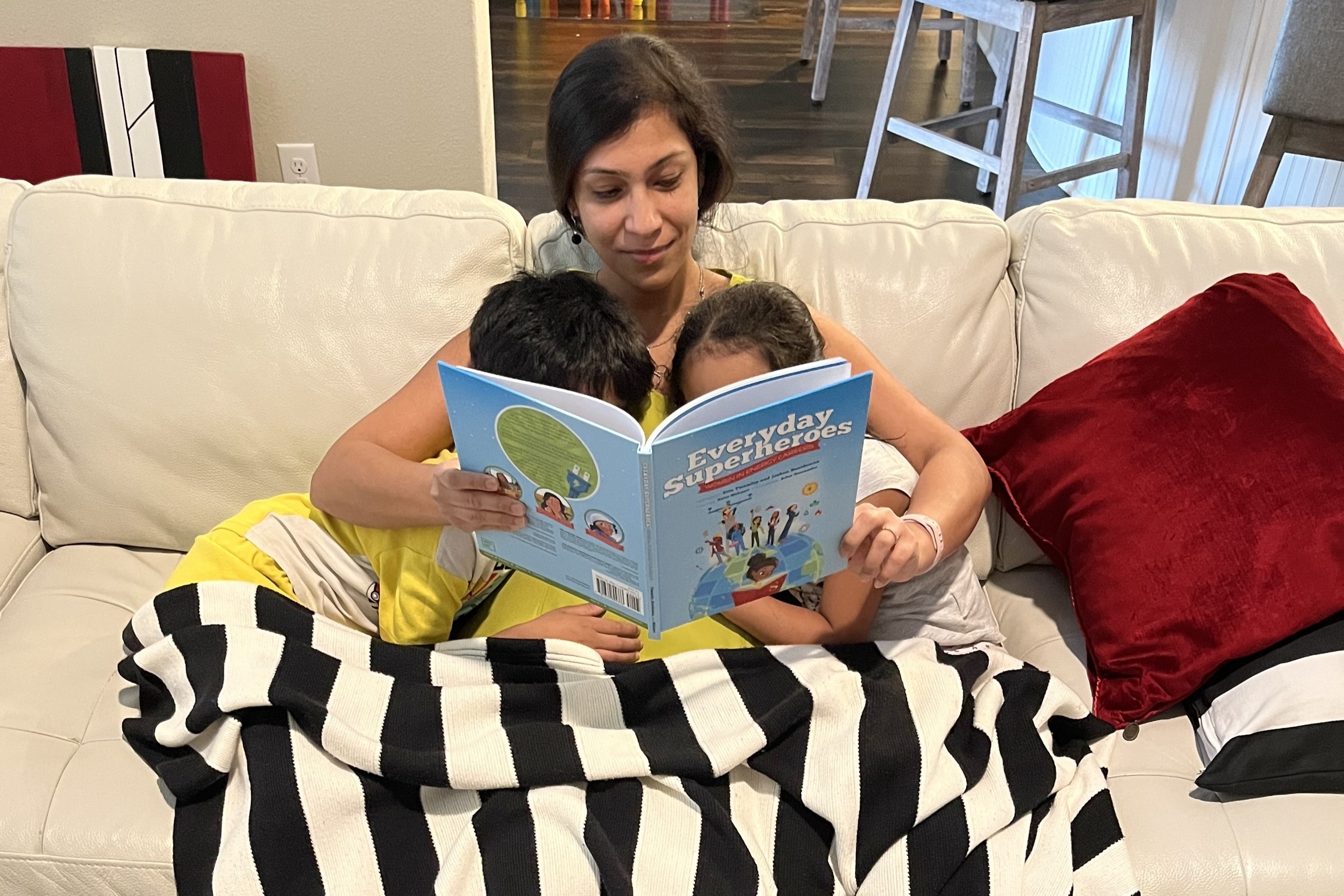 Vasudevan reading a book to her two kids on the couch