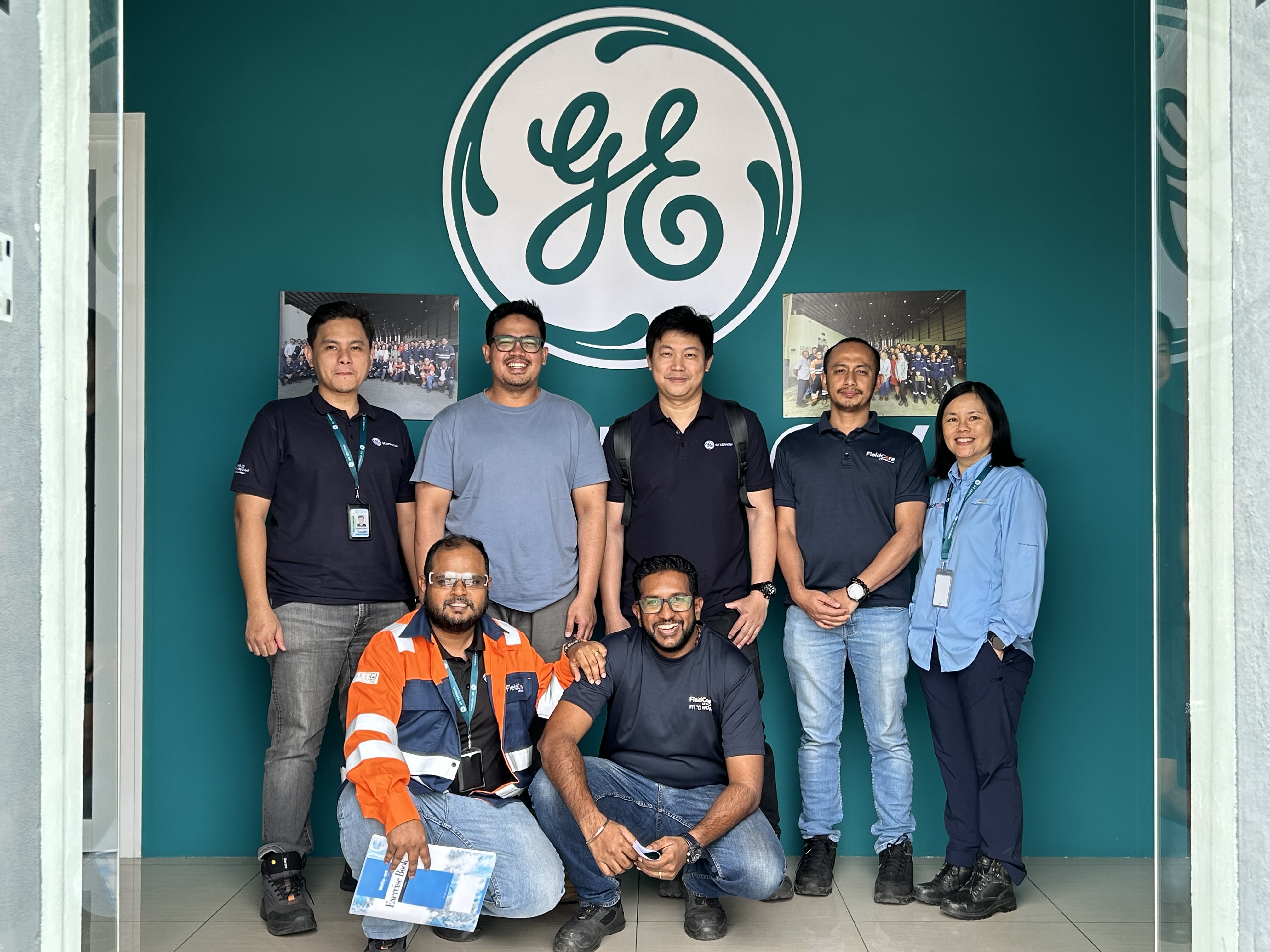 Group of men and Tan in front of teal wall with white GE Vernova symbol