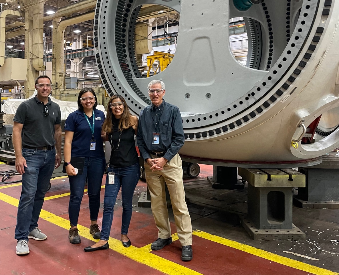 Veronica with three coworkers in front of a large piece of equipment