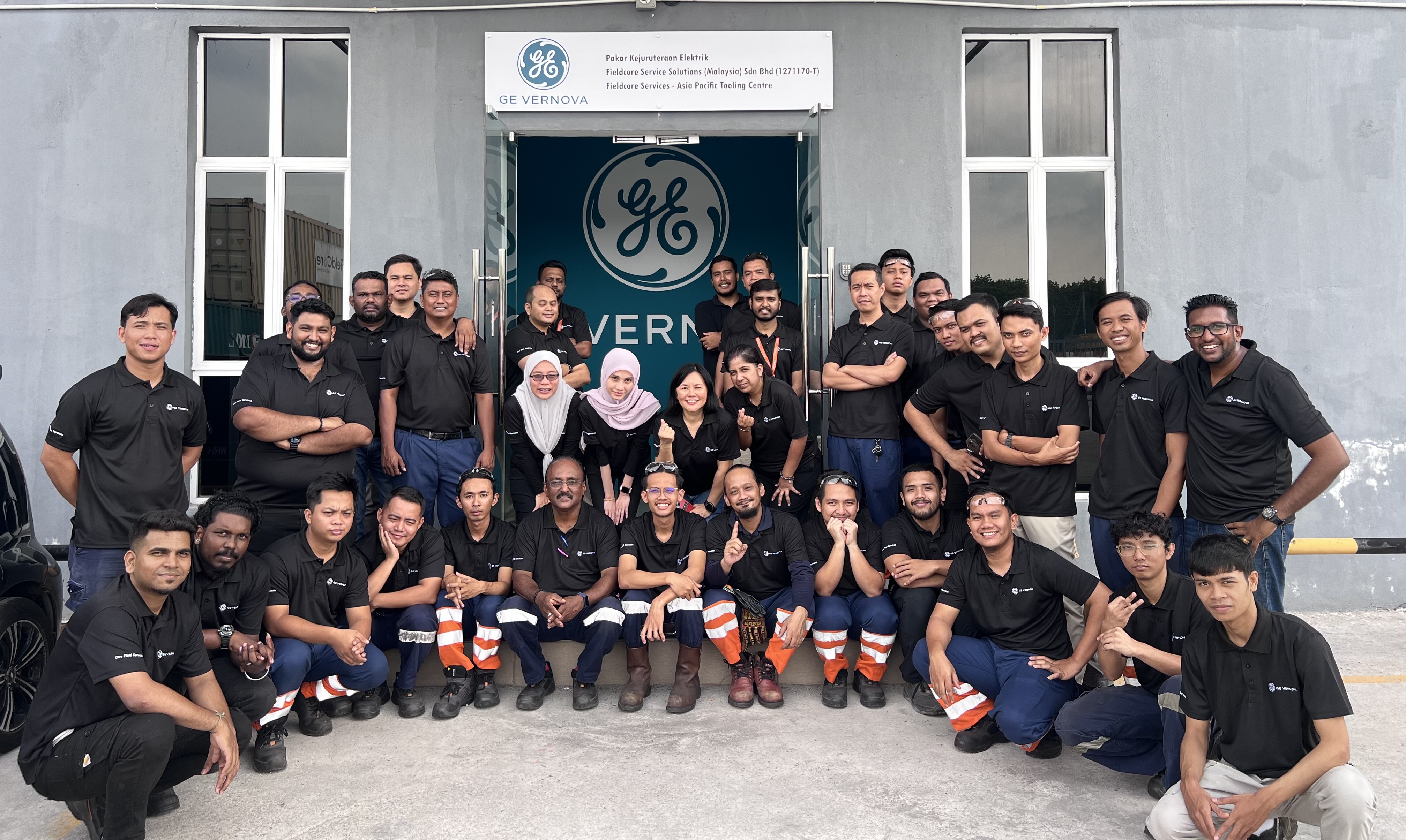 Group of GE Vernova employees in black company polos gathered outside for a group picture