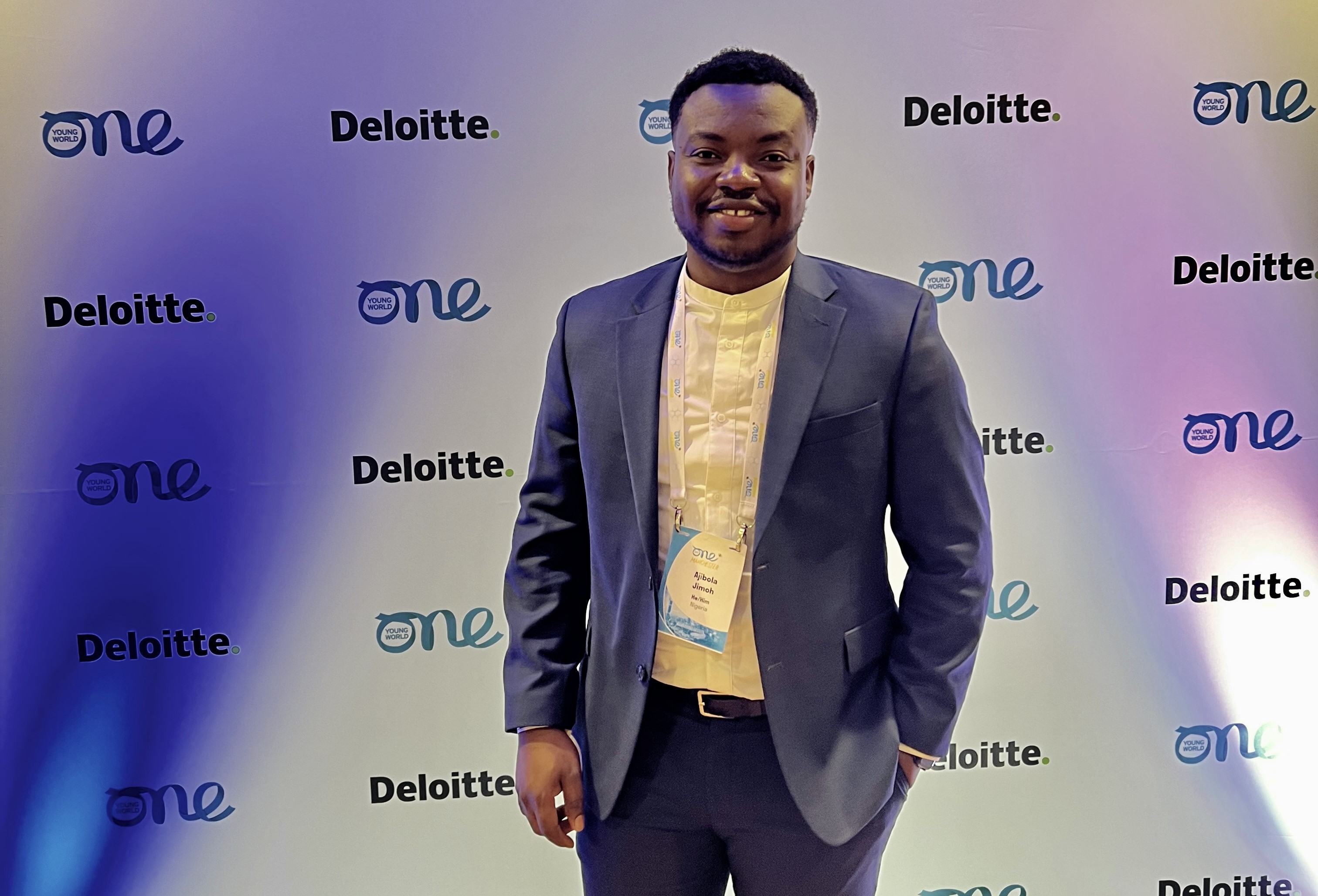 Man in front of a wall featuring the words Deloitte and One Young World