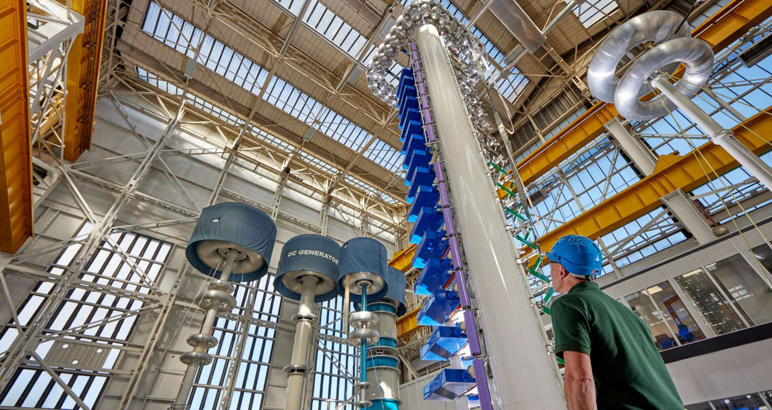 An employee stands in front of a circuit breaker manufactured at GE Vernova's Grid Solutions manufacturing facility in Charleroi, PA.